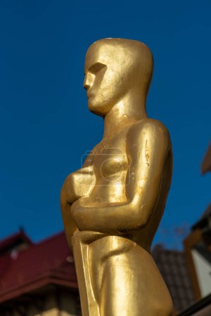 Foto de Detalle de la estatua del premio Óscar de oro de Hollywood sobre fondo azul cielo, de cerca. Concepto de éxito y victoria - Imagen libre de derechos