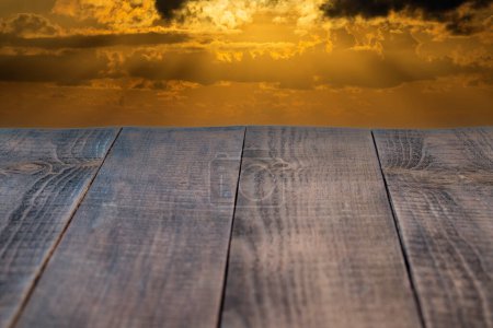 Photo for Empty wooden table and beautiful orange sky and clouds in background. Perspective brown wooden boards - Royalty Free Image