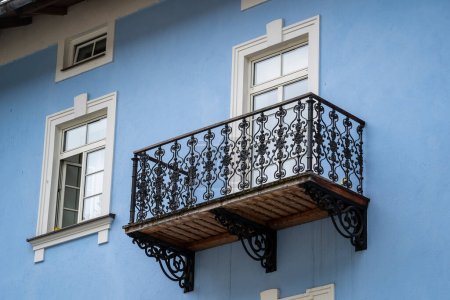 Foto de Ventanas con balcón en la fachada azul del edificio con adornos de hierro fundido en la calle en Austria - Imagen libre de derechos