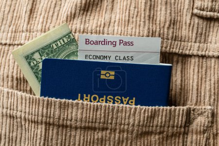 Foto de Dólares, pasaporte azul y tarjeta de embarque en el bolsillo de los pantalones de pana, de cerca. Concepto de viaje - Imagen libre de derechos