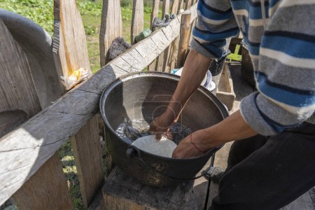 Téléchargez les photos : Un agriculteur ukrainien lave la vaisselle avec de l'eau propre dans la cour de la ferme, à proximité, à l'extérieur. Traditions rurales. Ukraine occidentale - en image libre de droit