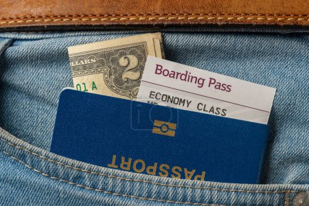 Téléchargez les photos : Dollars, passeport bleu et carte d'embarquement dans votre jean de poche, fermer. Concept de voyage - en image libre de droit