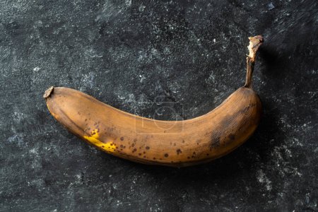 Téléchargez les photos : Banane trop mûre brune sur fond noir. Gros plan, vue de dessus - en image libre de droit