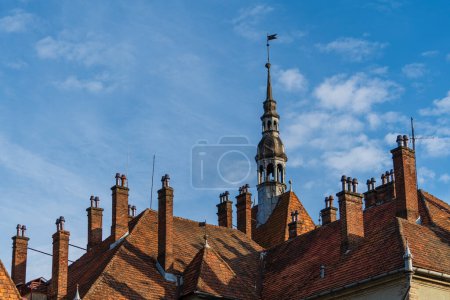 Foto de Detalle de un edificio antiguo con una gran torre con veleta en el techo en un día soleado sobre un fondo azul del cielo, de cerca. Ucrania Occidental - Imagen libre de derechos