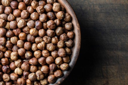 Photo for Dry hazelnuts in a ceramic plate on a wooden background. Heap of peeled hazelnuts kernels, top view, close up, copy space for text - Royalty Free Image