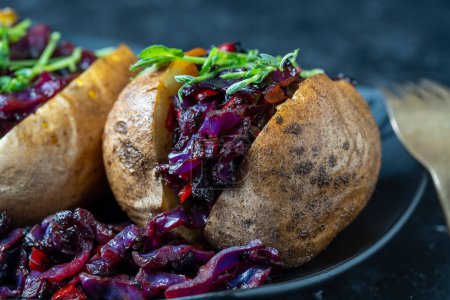 Photo for Stuffed potato with red cabbage, tomato, peppers and greens in black plate. Close up - Royalty Free Image