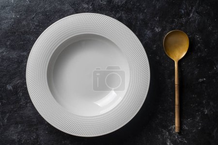 Téléchargez les photos : Assiette blanche vide et cuillère sur table de fond noire. Vue de dessus, gros plan - en image libre de droit