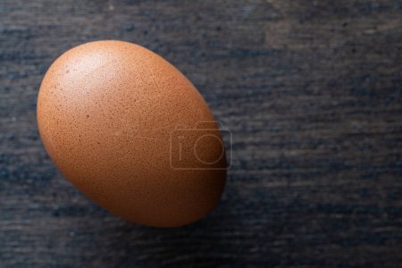Photo for Fresh one brown egg in a wooden background from agriculture farm, close up. Top view, copy space - Royalty Free Image
