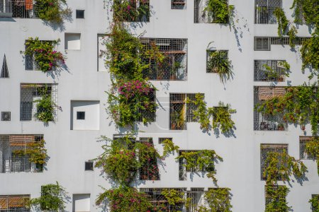 Photo for Facade of ecological buildings with green plants on the stone white wall of the house on the street, Vietnam - Royalty Free Image