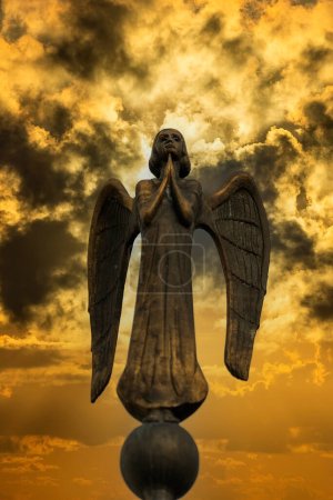 Photo for Detail of beautiful bronze statue of an angel with wings against the dark sky with clouds. Beautiful angel with a stormy sky background , close up - Royalty Free Image