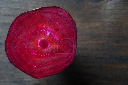 Photo for Fresh texture of a slice of beetroot on a wooden background, close up. Surface of red ripe beets. Top view, copy space - Royalty Free Image