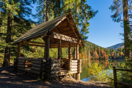 Foto de Gazebo de madera para relajarse cerca del lago Synevyr junto al bosque de otoño en las montañas de los Cárpatos en un día soleado de otoño. Ucrania Occidental - Imagen libre de derechos