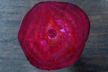Téléchargez les photos : Fresh texture of a slice of beetroot on a wooden background, close up. Surface of red ripe beets. Top view - en image libre de droit
