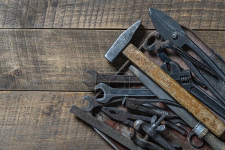 Photo for Vintage tools displayed in a old metal tray on a wooden board background, close up, top view, copy space. Dirty set old working tools - Royalty Free Image