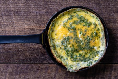 Téléchargez les photos : View of frying pan with fried eggs omelette on a wooden background , close up, top view - en image libre de droit