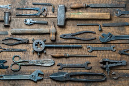 Photo for Vintage tools displayed on a background of wooden board, close up, top view. Dirty set old working tools - Royalty Free Image