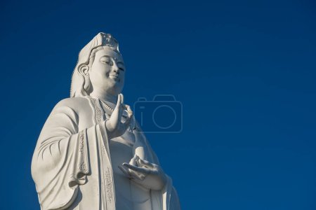 Téléchargez les photos : Détail de la statue de Lady Buddha dans un temple bouddhiste et fond bleu ciel à Danang, Vietnam. Fermer, copier l'espace - en image libre de droit