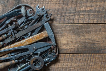Photo for Vintage tools displayed in a old metal tray on a wooden board background, close up, top view, copy space. Dirty set old working tools - Royalty Free Image