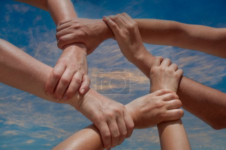 Téléchargez les photos : Beaucoup de mains des gens se connectent ou relient ensemble communauté de coopération sur fond de ciel bleu, gros plan. Concept de soutien d'équipe - en image libre de droit