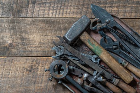 Foto de Vintage tools displayed in a old metal tray on a wooden board background, close up, top view, copy space. Dirty set old working tools - Imagen libre de derechos