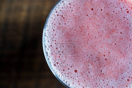 Foto de Healthy eating, food, dieting and vegetarian concept - glass of juice smoothie from strawberries. Pink strawberry shake with banana and honey on the wooden background, close up, top view - Imagen libre de derechos