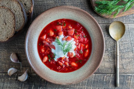 Téléchargez les photos : Ukrainian national dish red borsch in a ceramic plate on a wooden background. Beetroot soup is a national dish in Ukraine, close up, top view - en image libre de droit