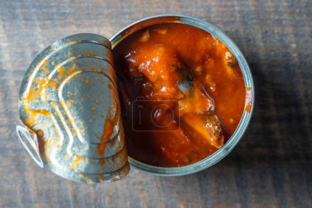 Photo for Open canned sprats in tomato sauce on a wooden background, close up, top view - Royalty Free Image