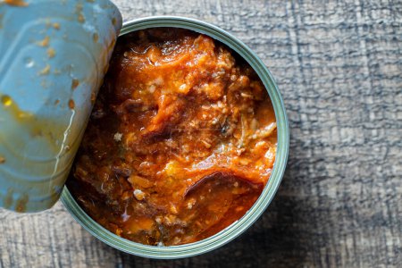 Téléchargez les photos : Open canned sardines in tomato sauce on a wooden background, close up, top view - en image libre de droit