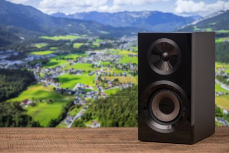 Téléchargez les photos : Haut-parleur acoustique noir sur une table en bois dans le contexte des montagnes alpines en Autriche. L'équipement musical, gros plan - en image libre de droit