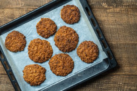 Téléchargez les photos : Delicious oatmeal cookies with walnuts on baking sheet, close up, top view - en image libre de droit