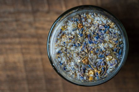Téléchargez les photos : Sea himalayan salt with dry lavender and chamomile flowers in a glass jar on wooden background, close up, top view - en image libre de droit