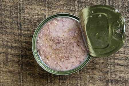 Foto de Open canned tuna in oil sauce on a wooden background, close up, top view - Imagen libre de derechos
