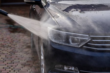 Téléchargez les photos : Laver une voiture bleue avec un nettoyeur d'eau haute pression, à l'extérieur, gros plan - en image libre de droit
