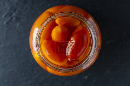 Photo for Canned tomatoes in glass jar , close up , home storage solution. Pickled tomato, top view - Royalty Free Image