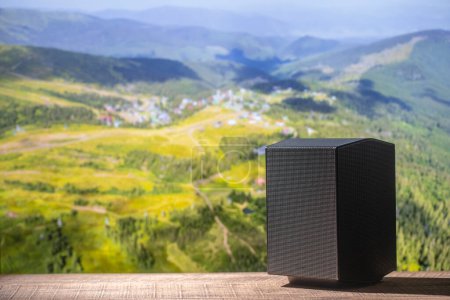 Téléchargez les photos : Haut-parleur acoustique noir sur une table en bois sur fond de montagnes des Carpates en Ukraine. L'équipement musical, gros plan - en image libre de droit
