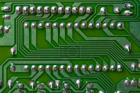 Foto de Una parte de una placa de computadora de circuito impreso verde con pistas. PCB sin componentes de radio. Fondo de placa de circuito impreso antiguo con traza de soldadura, primer plano, vista superior - Imagen libre de derechos