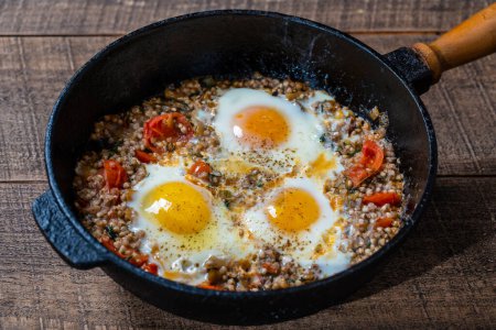 Photo for Boiled buckwheat with fried eggs, red peppers, tomato and onions, close up, Ukraine. Food background. Healthy food - Royalty Free Image