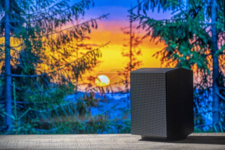 Téléchargez les photos : Haut-parleur acoustique noir sur une table en bois sur fond de forêt dans les Carpates à l'aube. L'équipement musical, gros plan - en image libre de droit