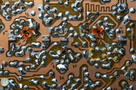 Photo for A part of a printed circuit computer board with tracks. PCB without radio components. Old printed circuit board background with soldering trace, close up, top view - Royalty Free Image