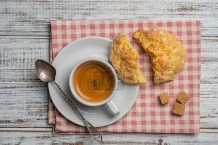 Téléchargez les photos : Tasse à café en porcelaine blanche avec soucoupe et biscuits au citron sur une table en bois, vue rapprochée, vue sur le dessus. Café chaud dans un petit déjeuner - en image libre de droit