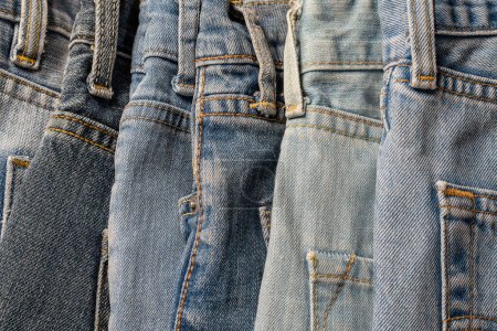 Téléchargez les photos : Plein de pantalons de jeans, gros plan. Fond en jean. Le concept d'achat, de vente, d'achat et de vêtements modernes à la mode - en image libre de droit