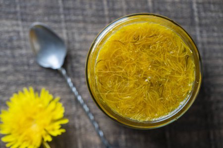 Photo for Sweet jam in glass jar jam from ripe yellow petals of dandelion flowers, orange, lemon and sugar, top view, close up. Dandelion famous medicinal plant - Royalty Free Image