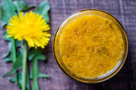 Photo for Sweet jam in glass jar jam from ripe yellow petals of dandelion flowers, orange, lemon and sugar, top view, close up. Dandelion famous medicinal plant - Royalty Free Image