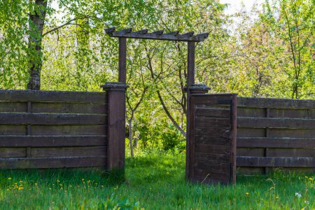 Photo for Wooden garden fence with open door and green grass on a spring day at backyard - Royalty Free Image