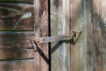 Téléchargez les photos : Clôture de jardin en bois avec une porte fermée en guichet sur un vieux crochet rouillé dans la cour, gros plan - en image libre de droit