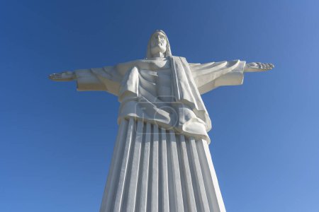 Photo for Detail 12-meter-high statue of Jesus Christ is a copy of a similar sculpture in Rio de Janeiro. Truskavets city, West Ukraine. Large statue of Jesus Christ with outstretched arms against the blue sky - Royalty Free Image
