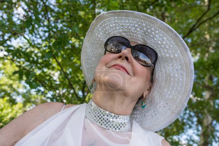 Photo for Portrait of a happy elderly woman 65 - 70 years old in a straw hat on the background of nature, close up - Royalty Free Image