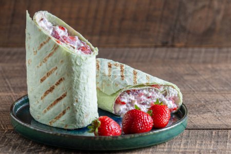 Photo for Pita bread wrapped with cottage cheese and red strawberries , close up - Royalty Free Image