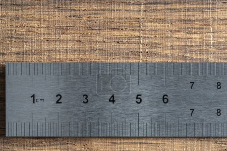 Photo for Fragment of a old metal ruler on wooden background, macro. Industrial steel ruler in centimeters, close up - Royalty Free Image