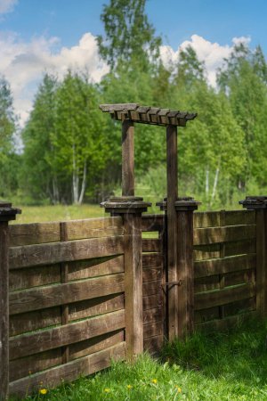 Photo for Wooden garden fence with closed door and green grass on a spring day at backyard - Royalty Free Image